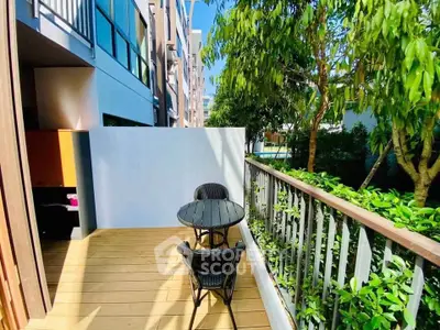 Charming balcony with outdoor seating and lush greenery in modern apartment complex.