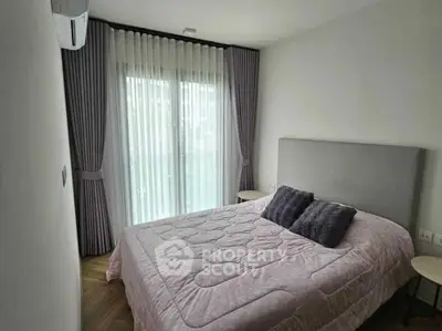 Cozy bedroom with modern decor and large window for natural light.