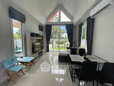 Spacious modern living room with high ceilings and large windows offering garden views, perfect for family gatherings.