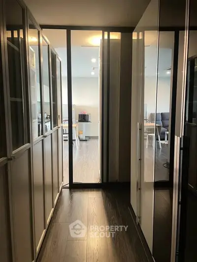 Modern apartment hallway leading to a bright living room with sleek furnishings.