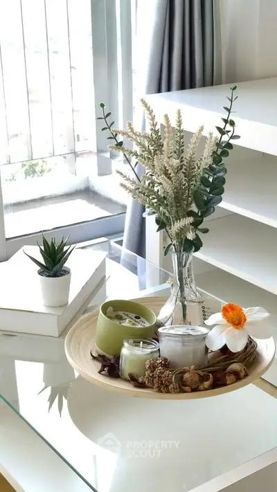 Stylish interior decor with elegant floral arrangement on a modern glass table near a bright window.