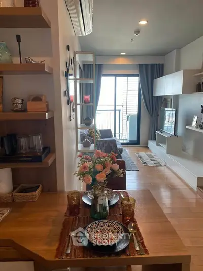 Stylish living room with balcony access, modern decor, and elegant dining setup.