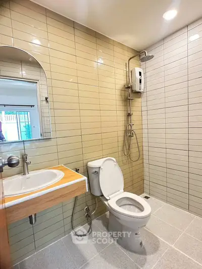 Modern bathroom with sleek tiles, shower, and contemporary fixtures.