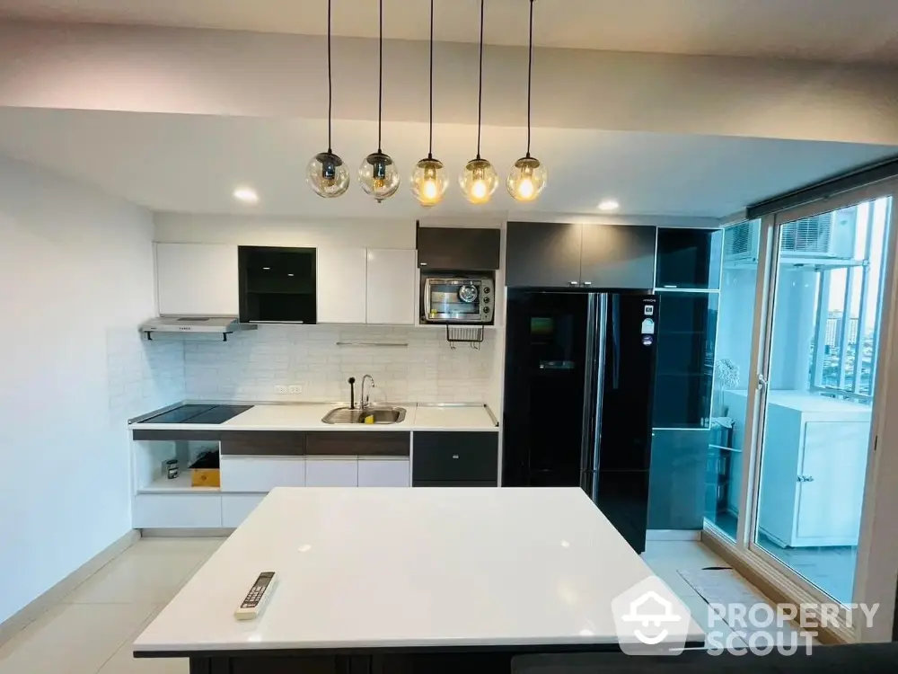 Modern kitchen with sleek black and white cabinetry, island, and stylish pendant lighting.