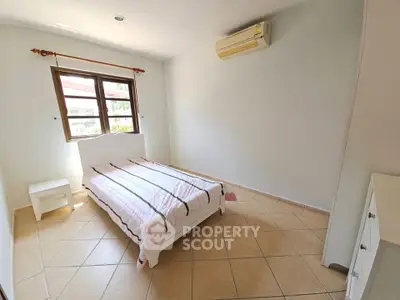 Bright bedroom with tiled floor and air conditioning, featuring a single bed and window view.