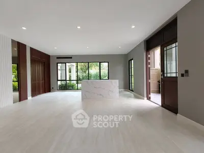 Spacious modern living room with large windows and elegant marble centerpiece.