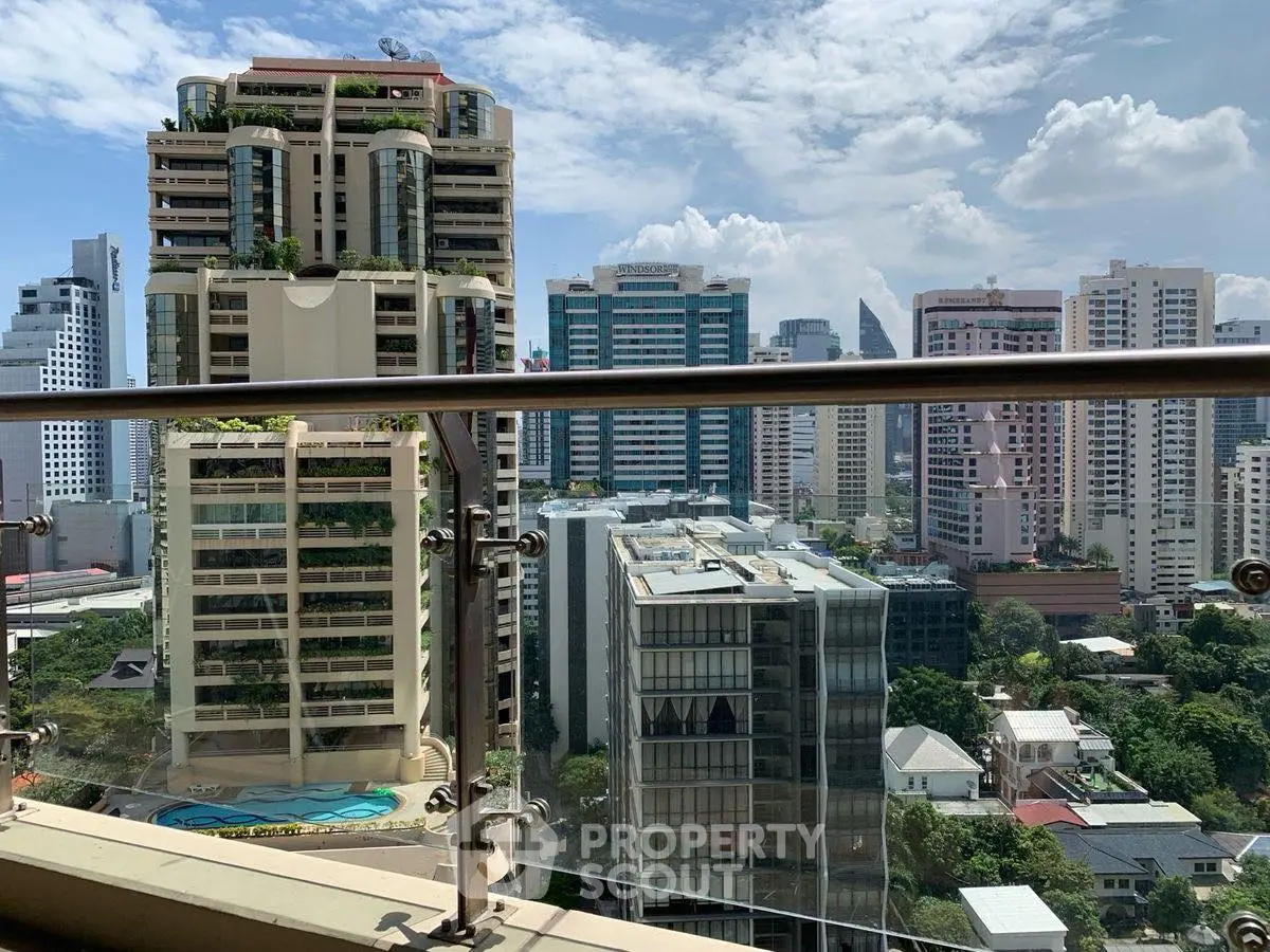 Stunning cityscape view from a high-rise balcony with modern skyscrapers and clear blue sky.