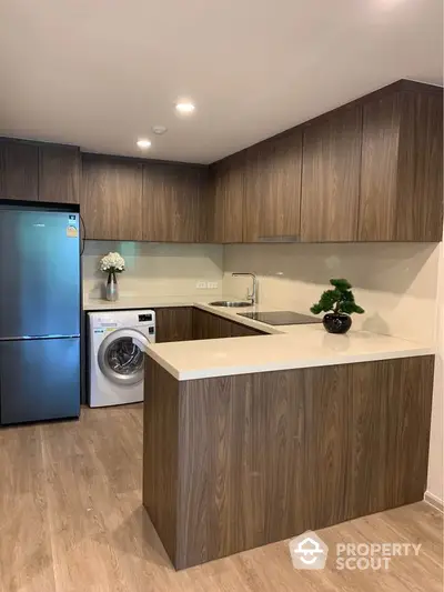 Modern kitchen with wooden cabinets, washing machine, and sleek appliances