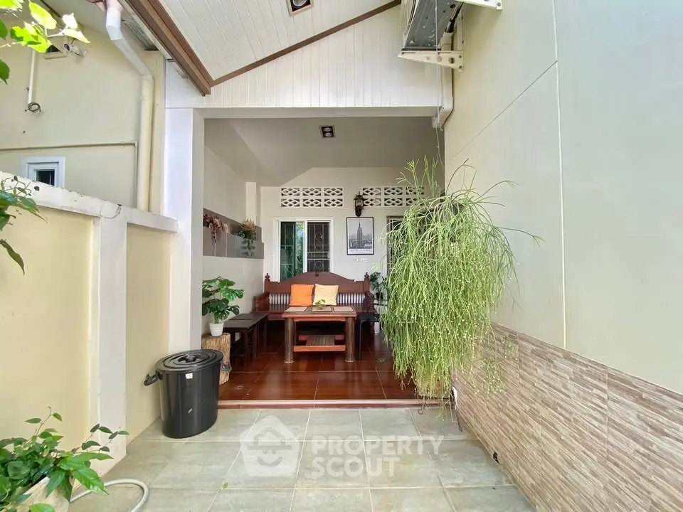 Charming outdoor seating area with lush greenery and cozy wooden furniture.
