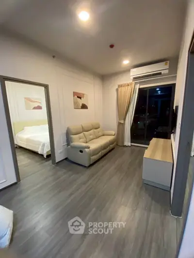 Modern living room with sleek flooring and cozy sofa, adjacent to a stylish bedroom, perfect for urban living.