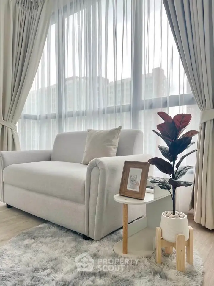Elegant living room with plush sofa, stylish side table, and large windows offering natural light.