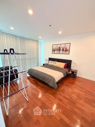 Spacious bedroom with wooden flooring and modern decor in a stylish apartment.