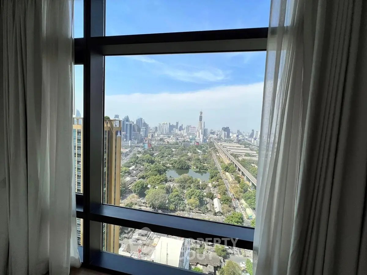 Stunning cityscape view from high-rise apartment window with lush greenery and skyline.