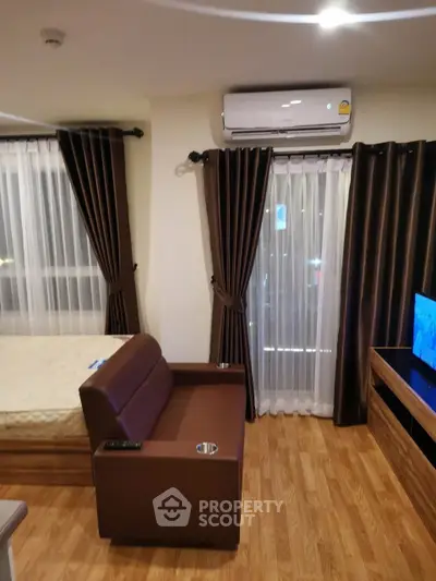 Modern living room with sleek brown sofa, wooden flooring, and large windows with elegant curtains.