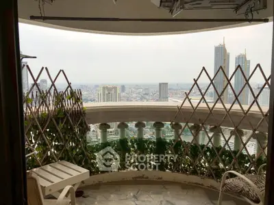 Stunning city view from a high-rise balcony with lush greenery and modern seating.