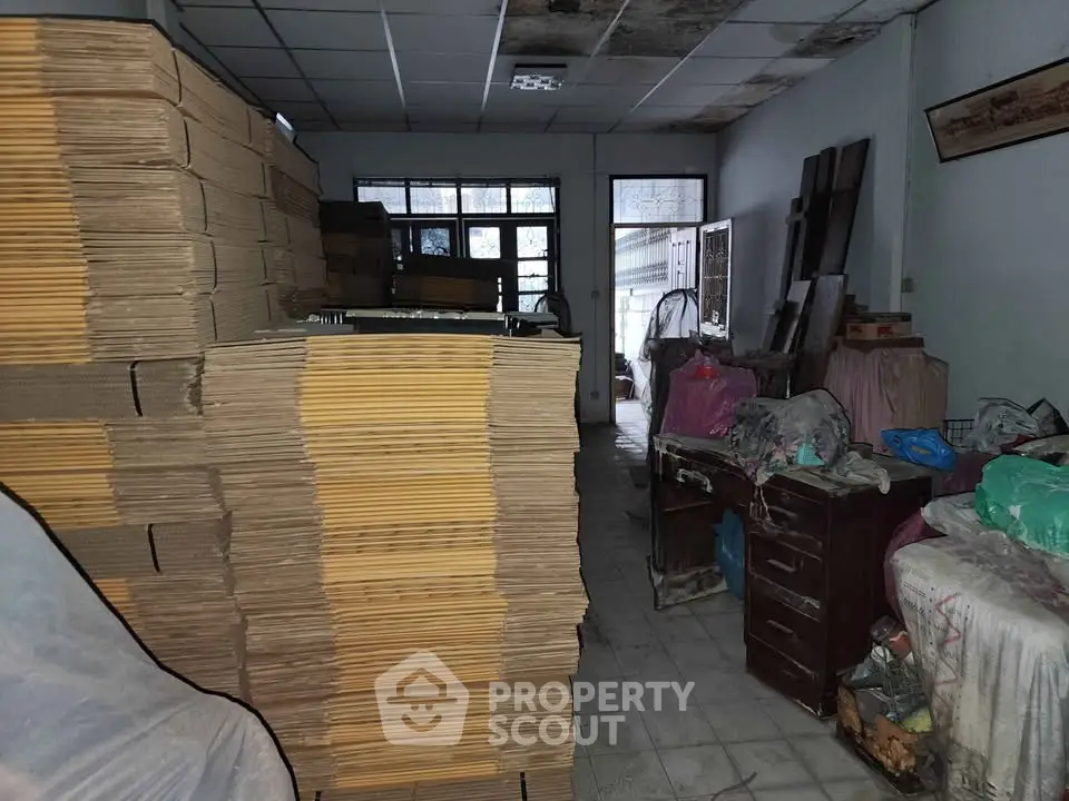 Spacious storage room with stacked cardboard boxes and covered furniture.