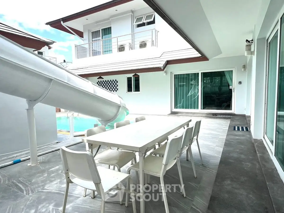 Luxurious modern home with poolside dining and water slide, perfect for entertaining.