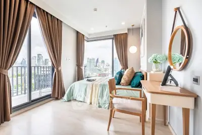 Bright bedroom with city view, elegant decor, and balcony access in modern apartment.