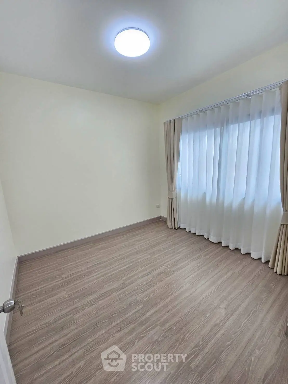 Spacious empty room with elegant curtains and modern flooring, perfect for customization.