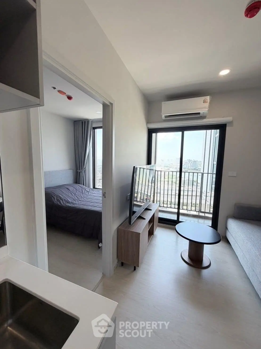 Modern apartment with open living room and balcony view, featuring sleek furniture and natural light.