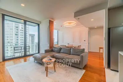 Spacious modern living room with large windows and city view, featuring elegant decor and cozy seating.
