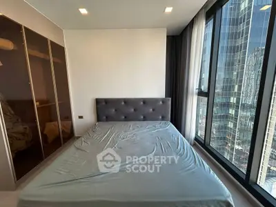 Modern bedroom with large windows offering stunning city views and sleek wardrobe design.