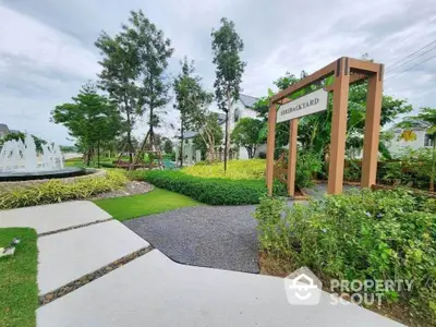 Beautiful garden entrance with lush greenery and fountain in serene residential area.