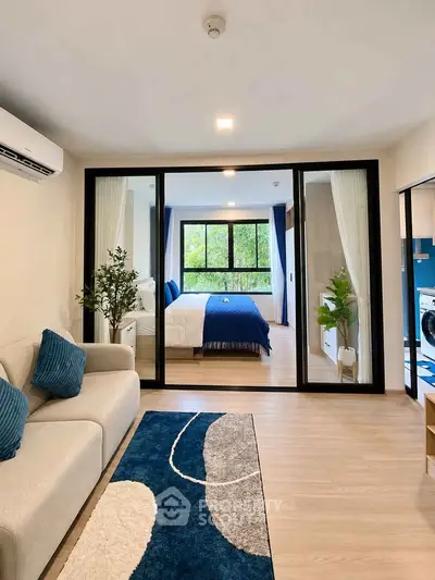 Modern living room with sliding glass doors leading to a stylish bedroom, featuring cozy decor and natural light.
