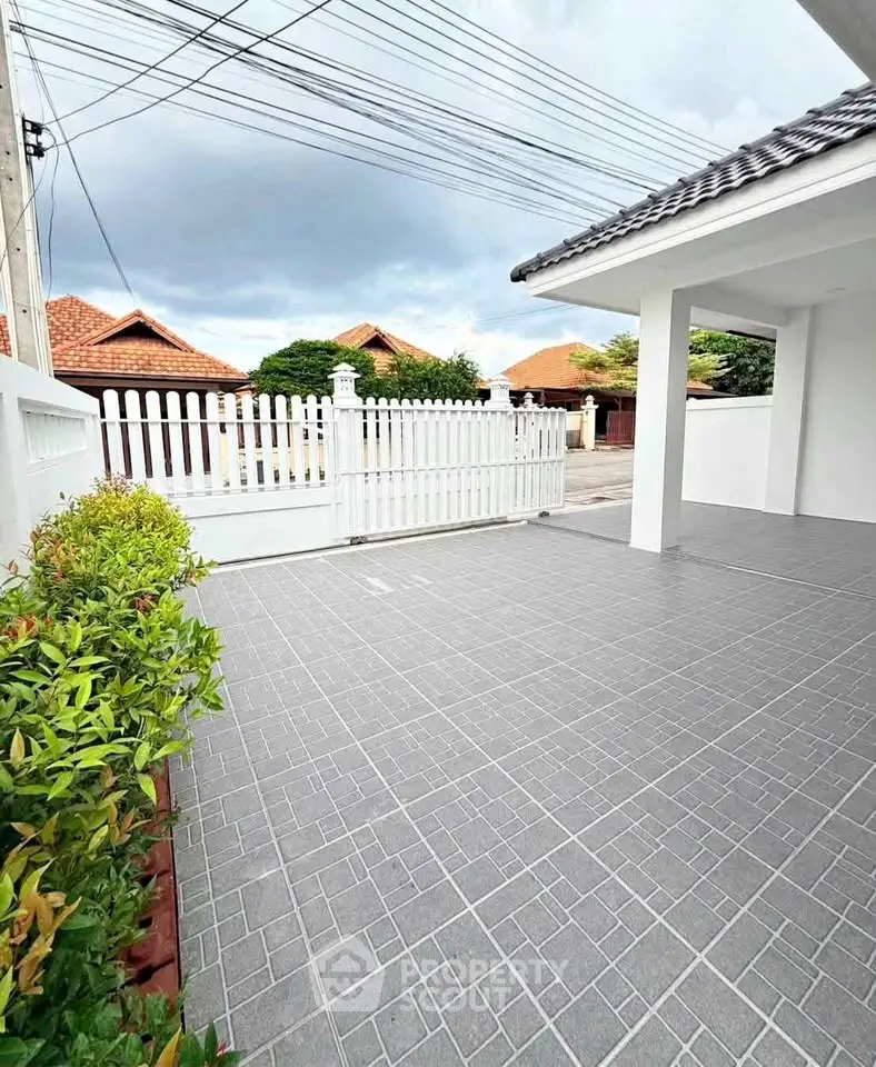 Charming residential exterior with tiled patio and white picket fence, perfect for outdoor relaxation.