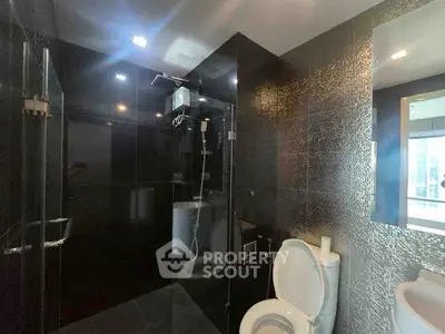 Luxurious modern bathroom with sleek black tiles and glass shower enclosure.