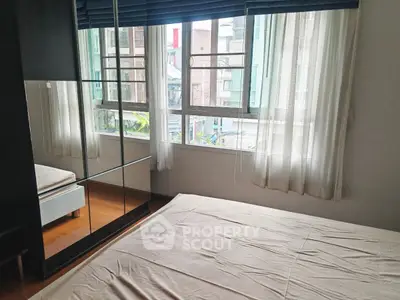 Bright bedroom with large windows and mirrored wardrobe in modern apartment.
