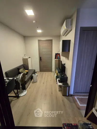 Modern living room with sleek design, featuring a comfortable sofa, air conditioning, and stylish flooring.