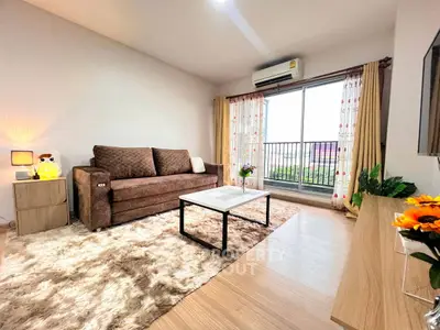 Cozy living room with plush sofa, stylish decor, and large window offering natural light.