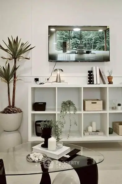 Modern living room with stylish decor, wall-mounted TV, and elegant shelving unit.