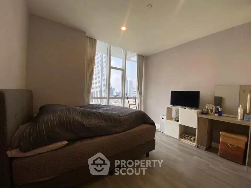 Spacious bedroom with city view, modern furnishings, and ample natural light.