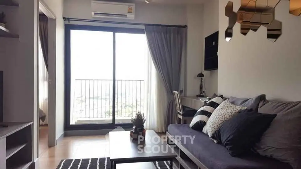 Modern living room with balcony view, stylish decor, and ample natural light in urban apartment.