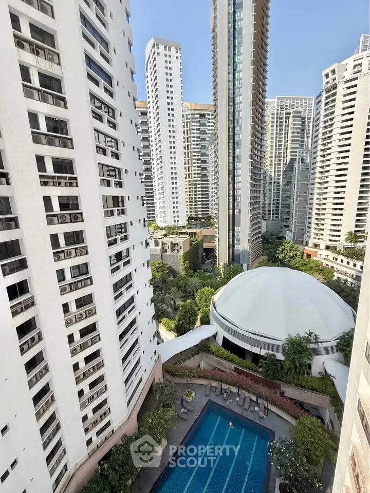 Stunning high-rise apartment view with pool and lush greenery in urban setting.