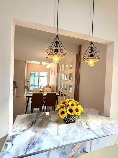 Stylish open-layout kitchen with marble countertop and elegant lighting, perfect for modern living.