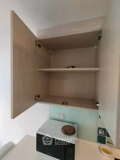Modern kitchen cabinet with open doors above a microwave, showcasing ample storage space.