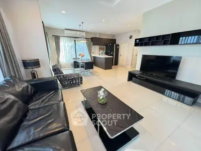 Spacious modern living room with sleek black furniture and open kitchen layout