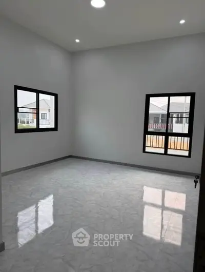 Spacious empty room with large windows and glossy tiled floor in modern home.