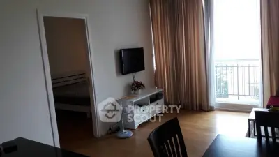Modern living room with balcony access and adjacent bedroom, featuring sleek furniture and natural light.