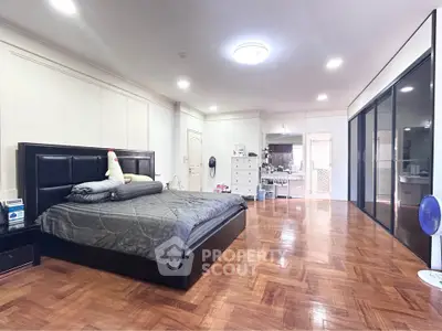Spacious bedroom with elegant parquet flooring and modern furnishings