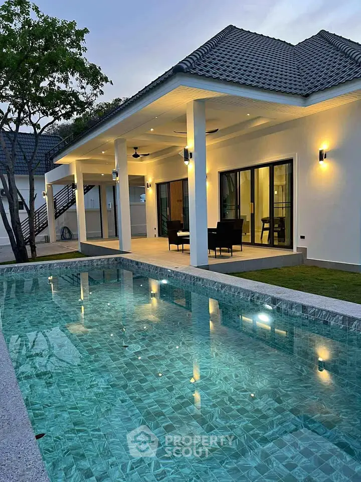 Luxurious modern villa with private pool and elegant outdoor seating area at dusk.
