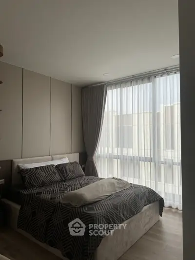 Modern bedroom with stylish decor and large window offering natural light