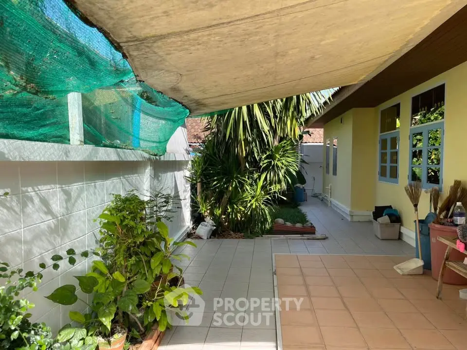 Charming garden patio with lush greenery and tiled flooring, perfect for outdoor relaxation.