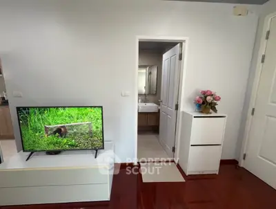 Cozy living room with TV and view into modern bathroom