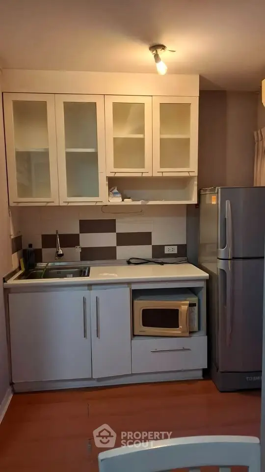 Compact kitchen with modern appliances and sleek cabinetry in a cozy apartment setting.