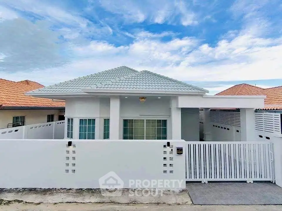 Charming white bungalow with modern design and spacious front yard under a clear blue sky.