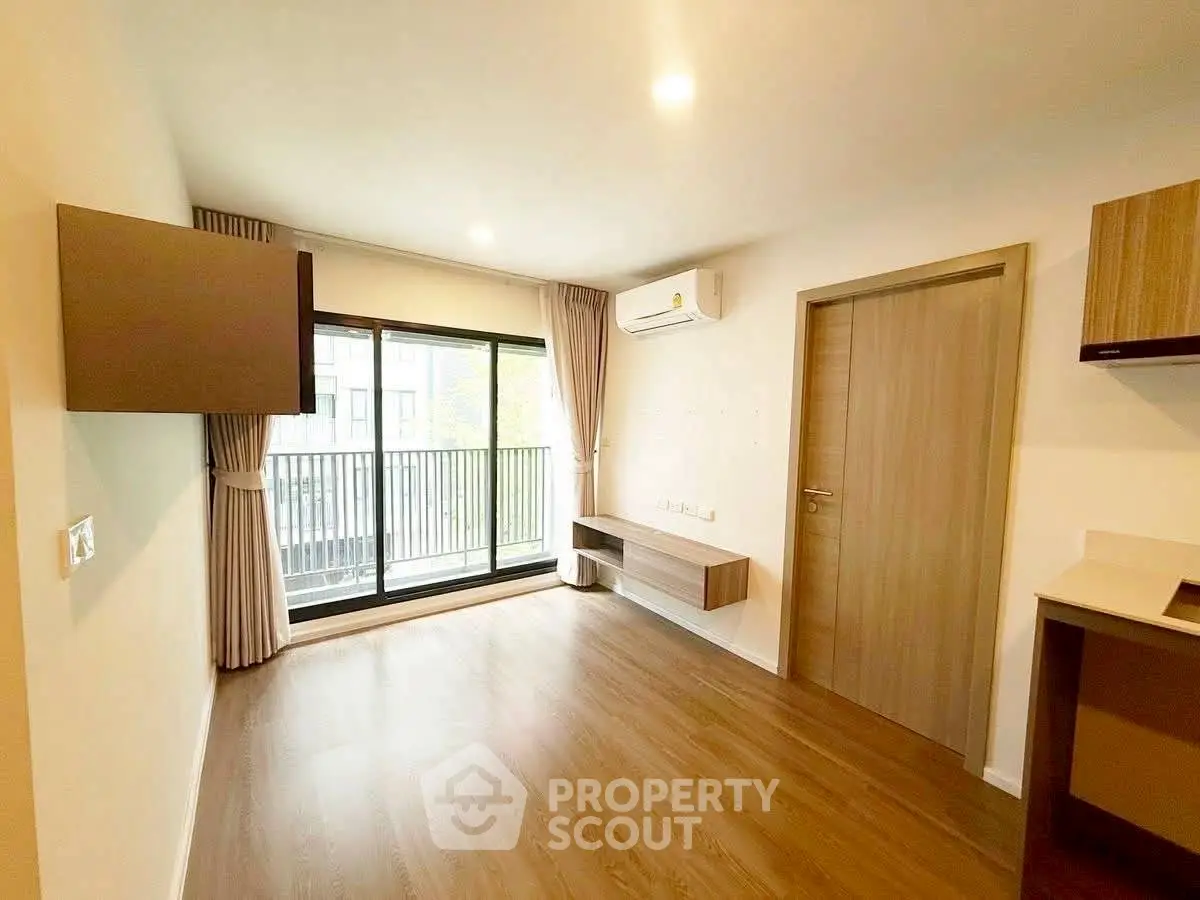 Modern living room with balcony access and wooden flooring in a stylish apartment.